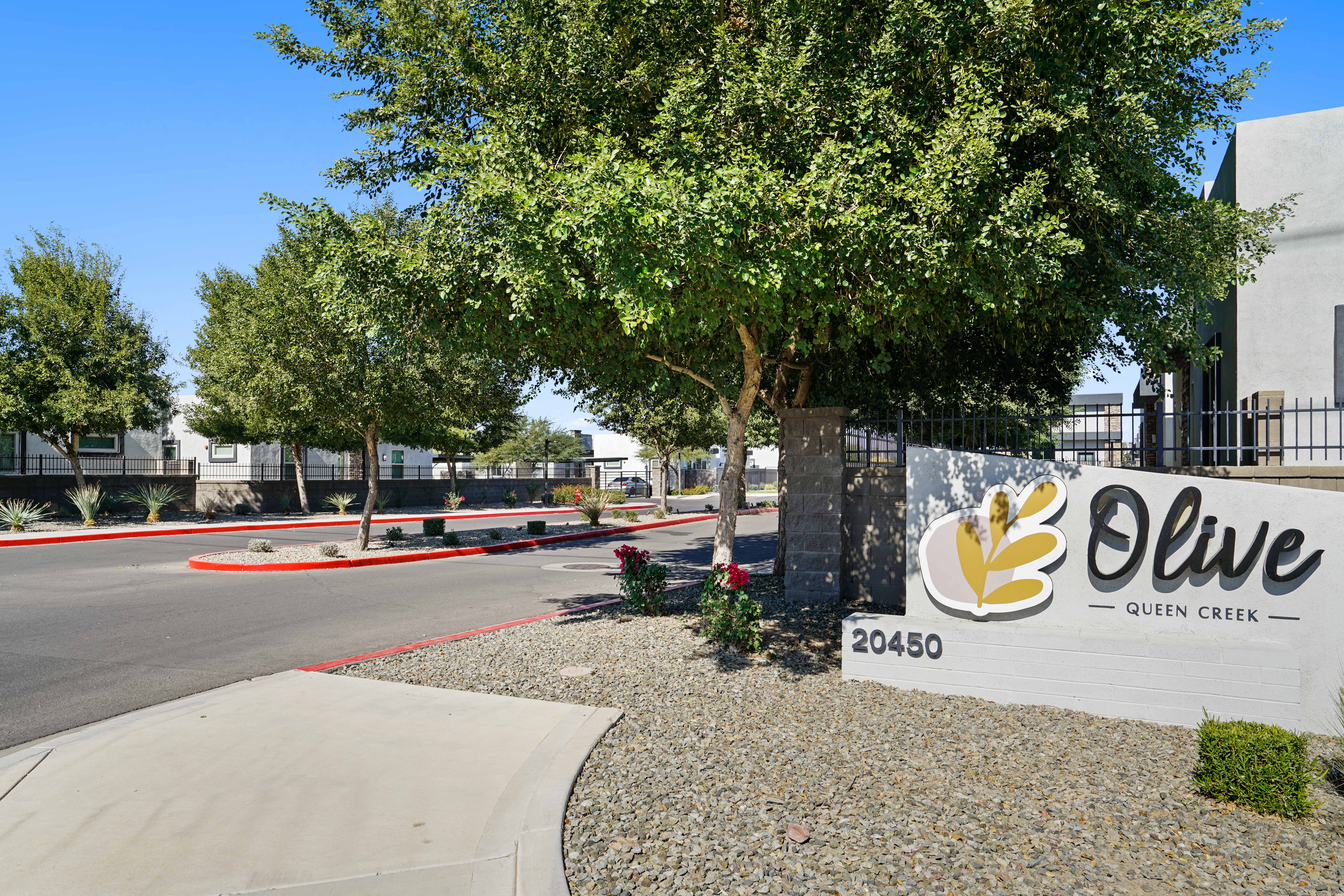 a sign in front of an office building with a tree at Olive Queen Creek Apartments, Queen Creek, AZ, 85142